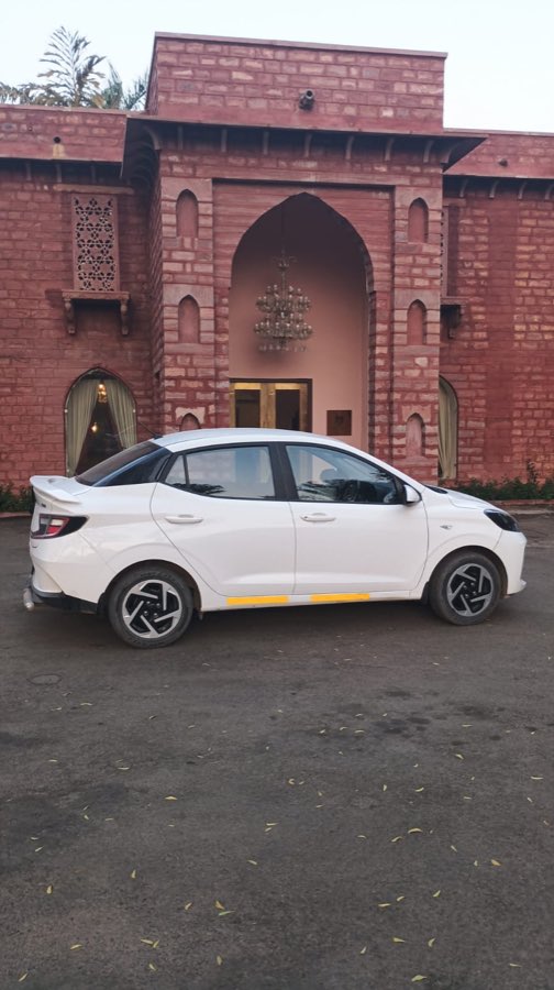 A sedan outside a red sandstone haveli