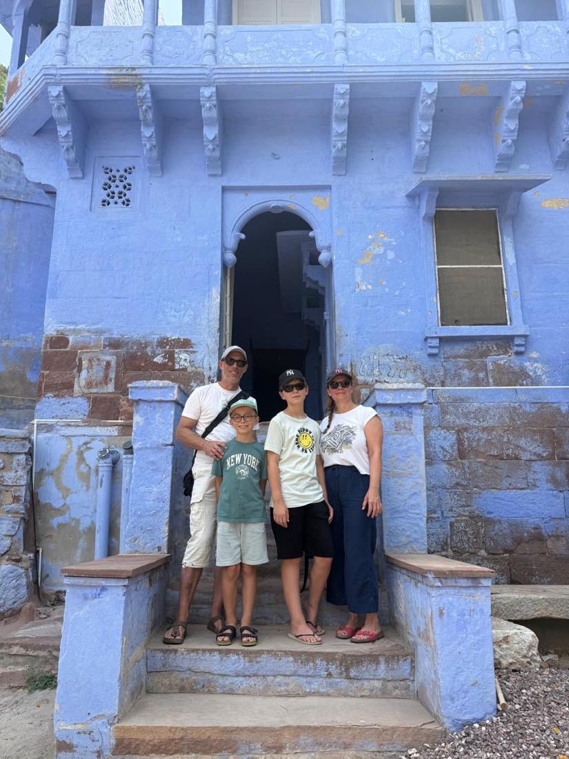 A family on the steps of a blue haveli